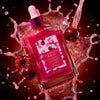 A bottle of Glampton Crushed Cherry  body oil bottle with a cherry design on a dark cherries  background