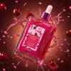 A bottle of Glampton Crushed Cherry  body oil bottle with a cherry design on a dark cherries  background