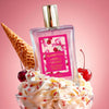 Shimmer Fragrance Mist bottle labeled ‘Glampton Crushed Cherry’ placed on whipped cream with cherry pieces, an ice cream cone, and whole cherries on a pink background.