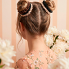 A young woman with styled hair with brown, black and cream scrunchies in a floral dress surrounded by flowers