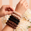 Hands holding three hair scrunchies against a floral background