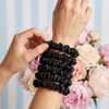 Black hair scrunchies on a wrist with a floral background