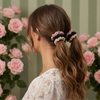 Woman with styled hair featuring scrunchies against a floral background