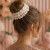 Woman with a bun held by multiple scrunchies against a blurred floral background