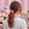 Woman with a pink scrunchie in her hair against a pink floral background
