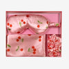 Glampton satin sleep set in cherry print displayed inside the open pink box, including satin pillowcase, eye mask, and matching scrunchies.